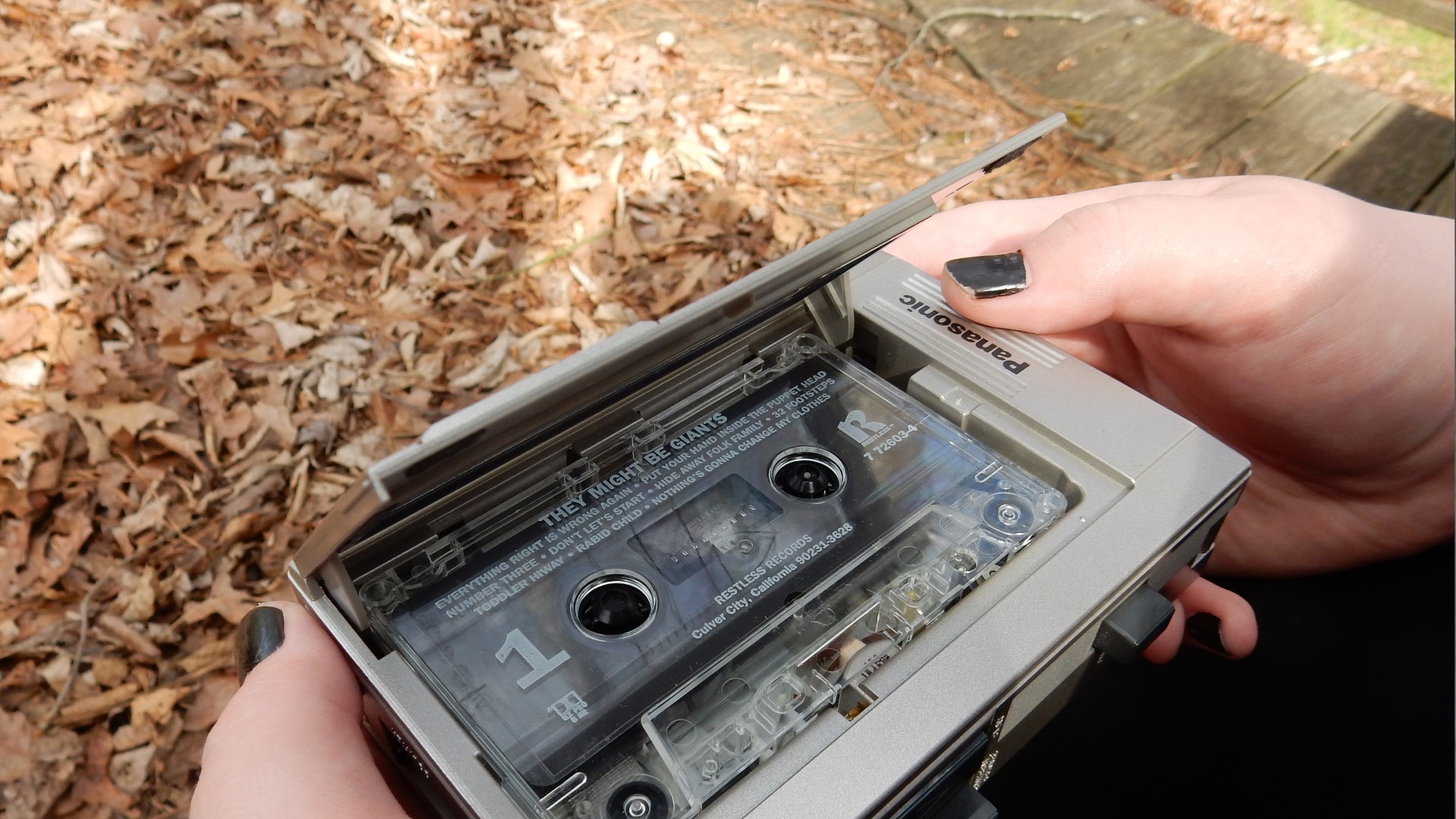 an image of my hands holding a cassette player, the tape in it is They Might Be Giants' self-titled album